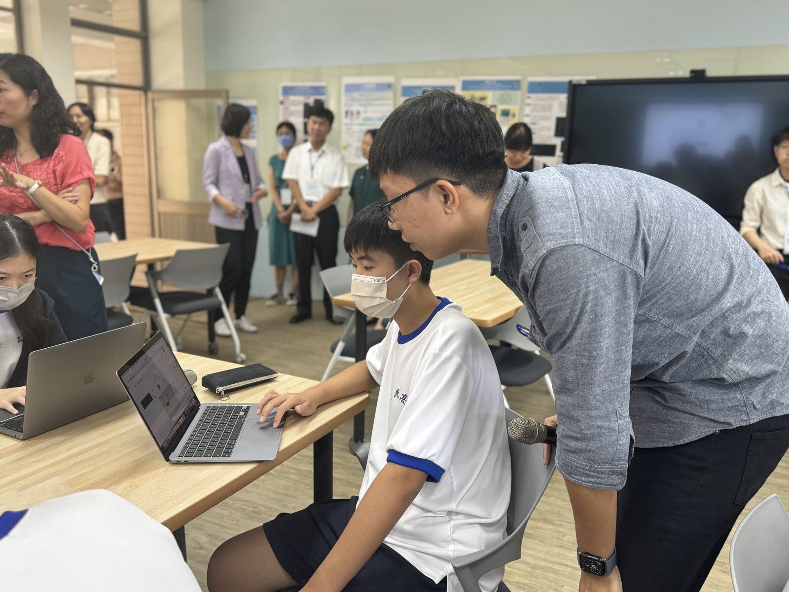 2024/10/24 專題研究公開授課，講師逐台指導程式，後方為評審專家與長官觀課。