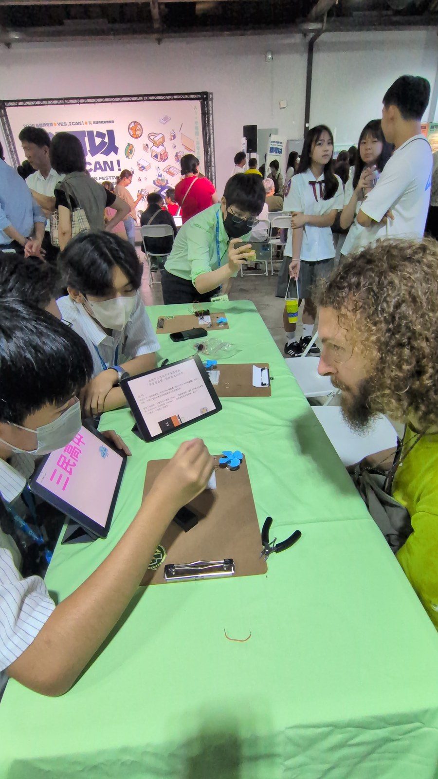 以英語向外籍來賓解說電晶體應用，平板畫面為「學會電晶體　開啟寬廣未來」。