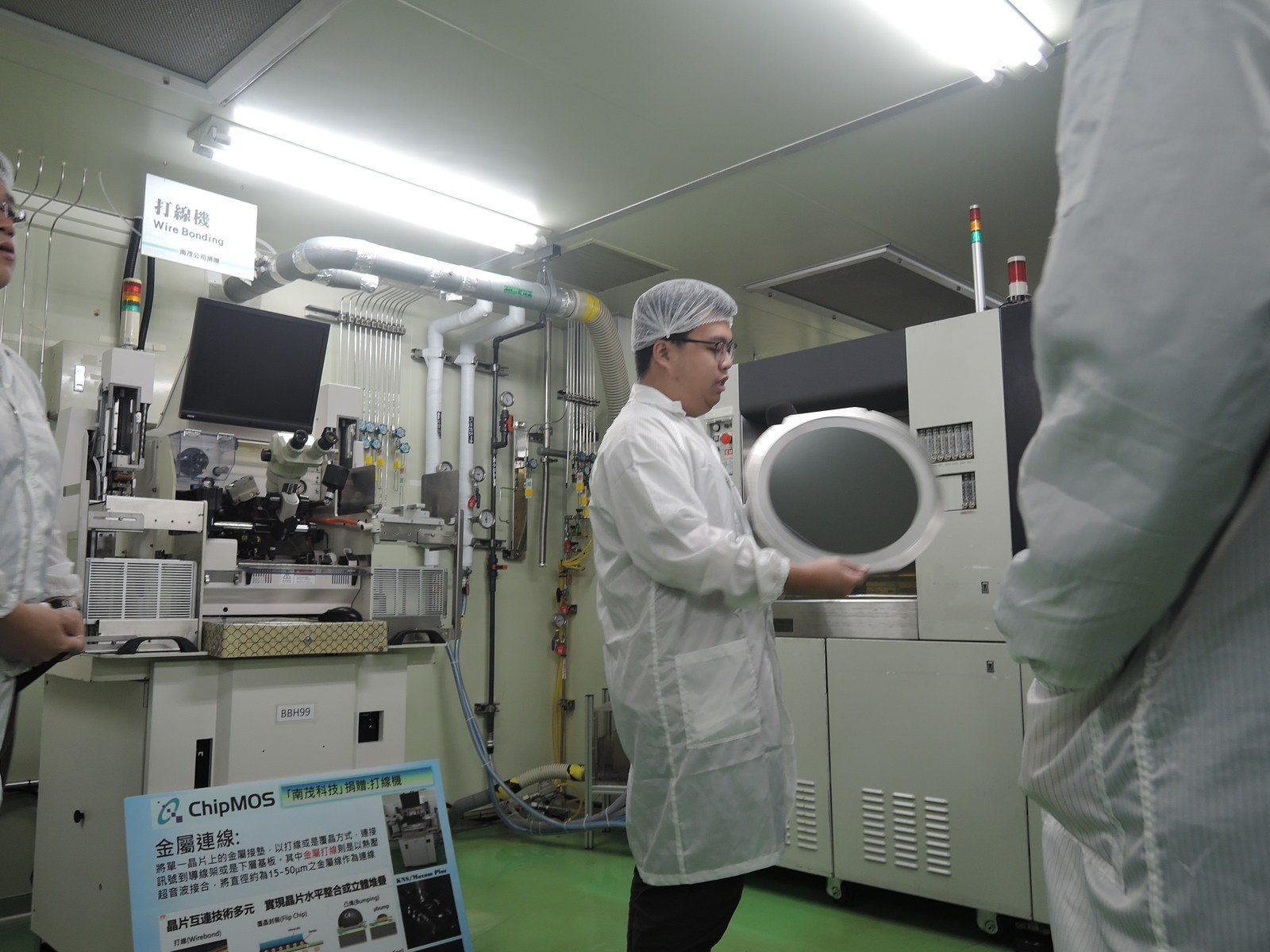 講師展示晶圓，於南茂科技捐贈的打線機（Wire Bonder）前解說封測製程。